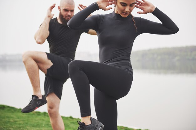 Una giovane coppia si diverte a fare sport al mattino all'aperto. Riscaldati prima dell'esercizio