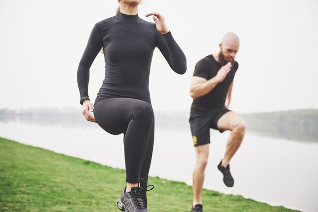 Una giovane coppia si diverte a fare sport al mattino all'aperto. Riscaldati prima dell'esercizio