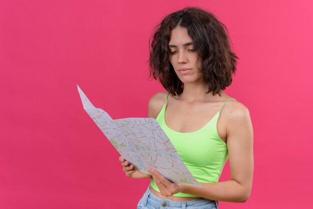 Una giovane donna adorabile con i capelli corti in top verde guardando una mappa