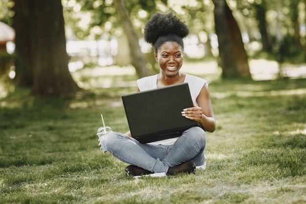 Una giovane donna afroamericana che guarda in un computer portatile al parco