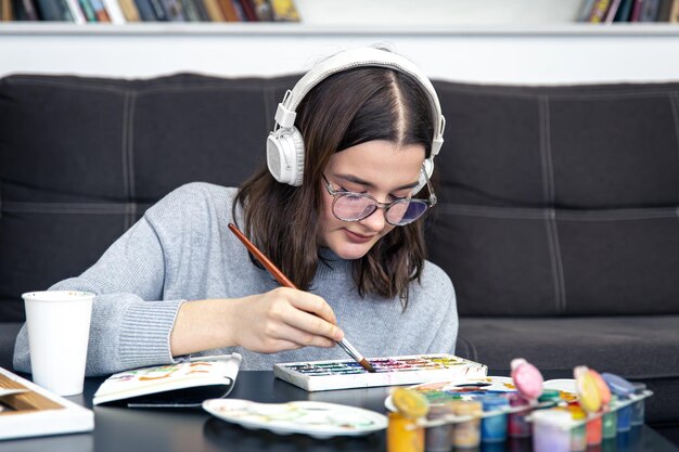 Una giovane donna alla moda disegna con le vernici all'interno della casa