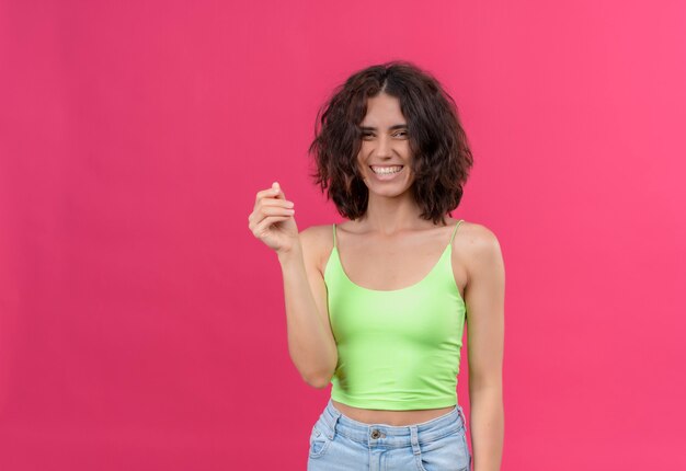 Una giovane donna attraente felice con i capelli corti nel sorridere verde della parte superiore del raccolto