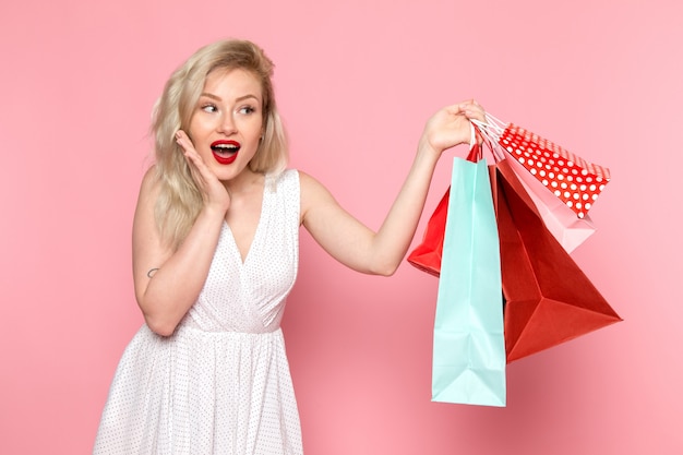 Una giovane donna bella vista frontale in abito bianco tenendo i pacchetti di shopping con il sorriso sul suo viso