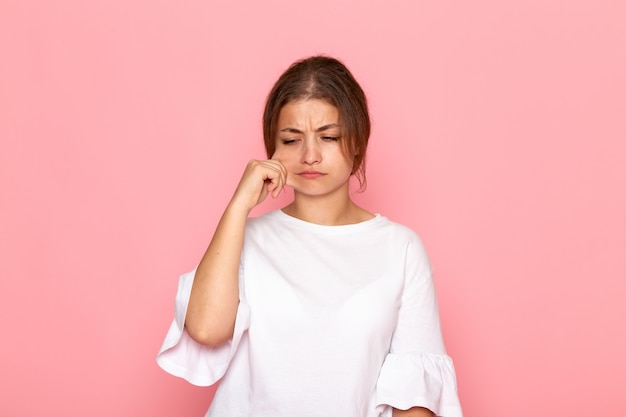 Una giovane donna bella vista frontale in camicia bianca, togliendosi la guancia