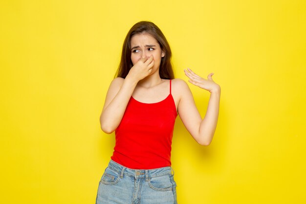 Una giovane donna bella vista frontale in camicia rossa e blue jeans che copre il naso