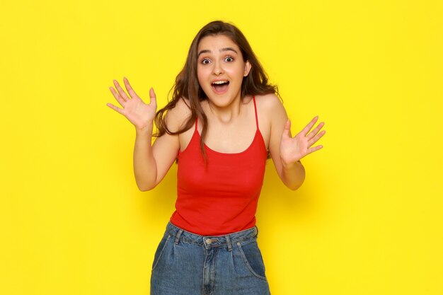 Una giovane donna bella vista frontale in camicia rossa e blue jeans con espressione eccitata