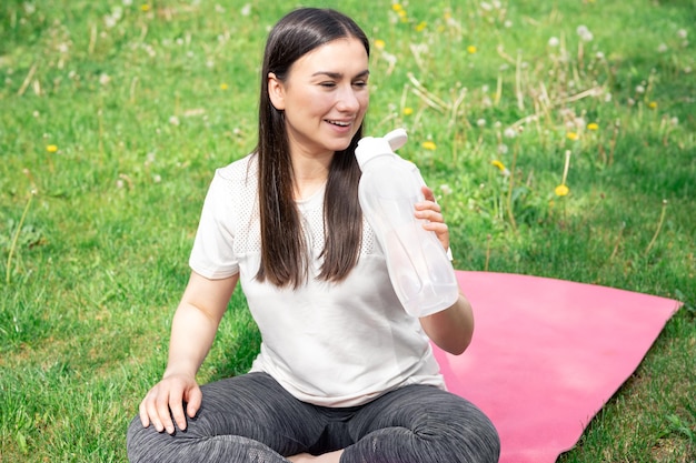 Una giovane donna che beve acqua dopo aver esercitato all'aperto