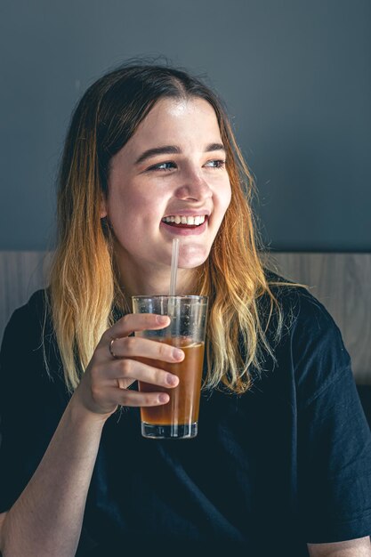 Una giovane donna che beve una bevanda fredda al caffè estivo con ghiaccio e succo d'arancia