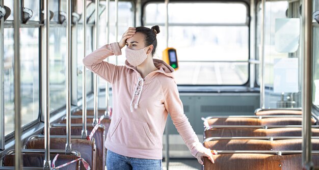 Una giovane donna che indossa una maschera è sola sui mezzi pubblici durante la pandemia di coronavirus.