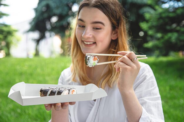 Una giovane donna che mangia sushi in natura maki roll primo piano