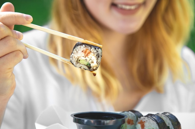 Una giovane donna che mangia sushi in natura maki roll primo piano