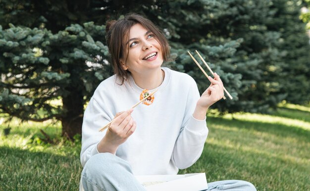 Una giovane donna che mangia sushi nel parco picnic in natura