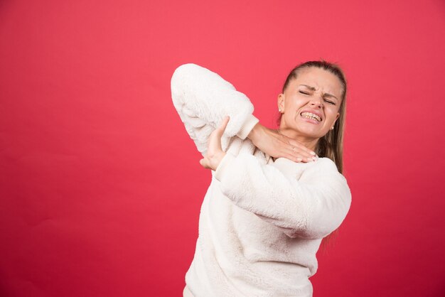 Una giovane donna che tiene la gola e soffre di dolore