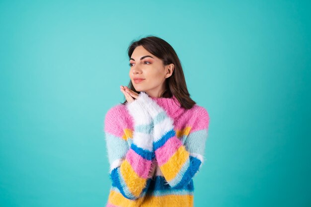 Una giovane donna con un luminoso maglione multicolore su sfondo blu sorride graziosamente