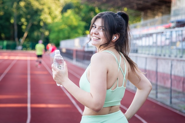 Una giovane donna con una bottiglia d'acqua in allenamento allo stadio
