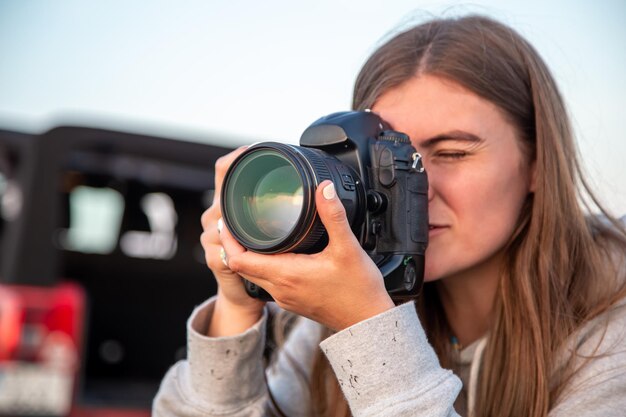 Una giovane donna con una macchina fotografica professionale scatta una foto in natura