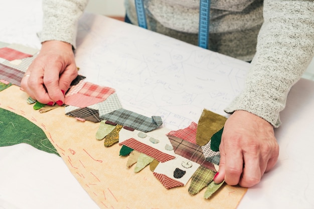 Una giovane donna creativa che crea paesaggi di rappezzatura del tessuto su carta