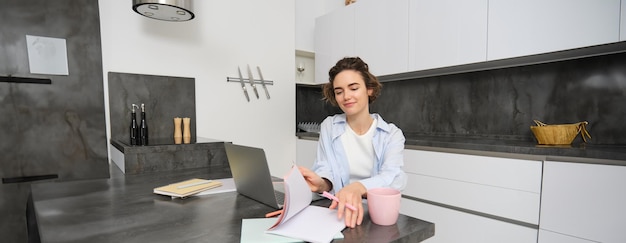 Una giovane donna determinata sfoglia le pagine del suo libro di lavoro studiando l'apprendimento online a distanza da