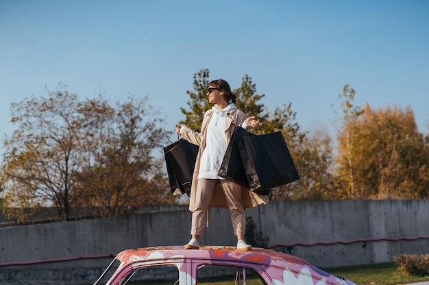 Una giovane donna è in piedi in una macchina con le borse in mano