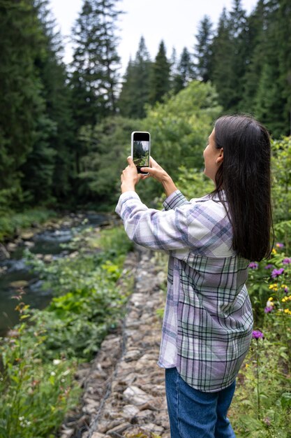 Una giovane donna fa una foto in montagna nella foresta su uno smartphone