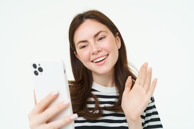 Una giovane donna felice agita la mano alla telecamera dello smartphone per salutare gli spettatori sull'app dei social media