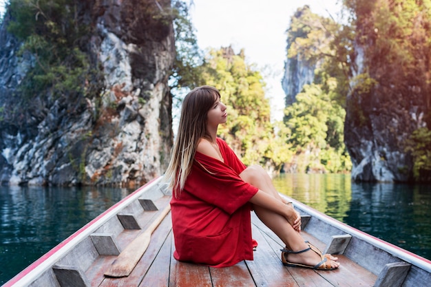 Una giovane donna in bikini è seduta su una piccola barca vicino a un'isola tropicale. Vacanze estive.