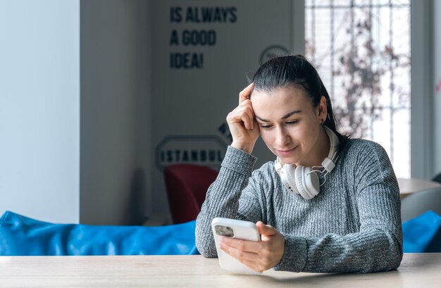 Una giovane donna in cuffie bianche e con uno smartphone