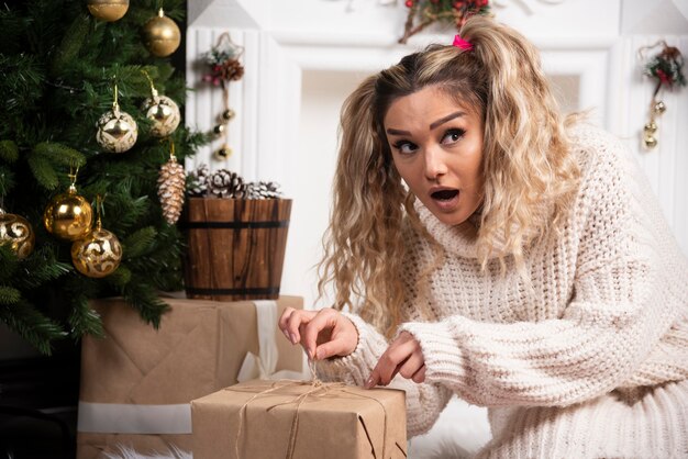 Una giovane donna in maglione bianco che mostra due scatole di regali di Natale.