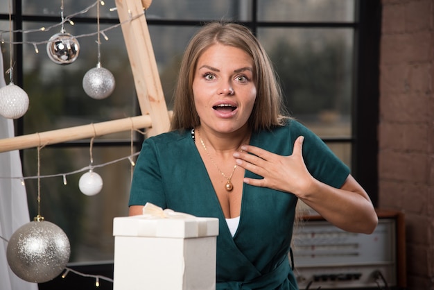 Una giovane donna in piedi con un regalo di Natale a casa