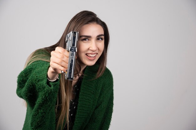 Una giovane donna in possesso di uno strumento di lavoro su uno sfondo grigio.