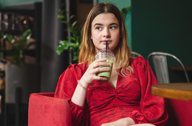 Una giovane donna in un caffè beve una bevanda verde latte ghiacciato