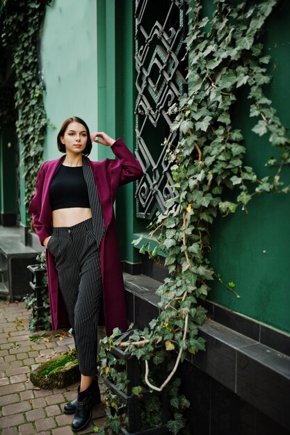 Una giovane donna modello bella ed elegante dalle gambe alte al cappotto claret