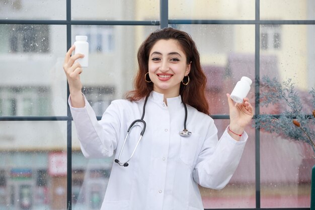 Una giovane donna operaia sanitaria che tiene la capsula della medicina e ridendo Foto di alta qualità