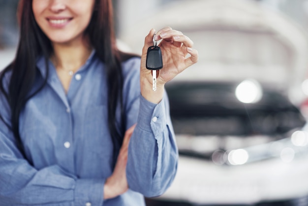 Una giovane donna prende un'auto dal centro servizi auto. È felice perché il lavoro è svolto perfettamente