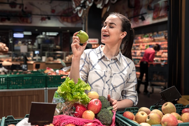 Una giovane donna sceglie frutta e verdura in un supermercato