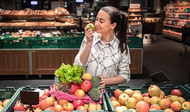 Una giovane donna sceglie frutta e verdura in un supermercato