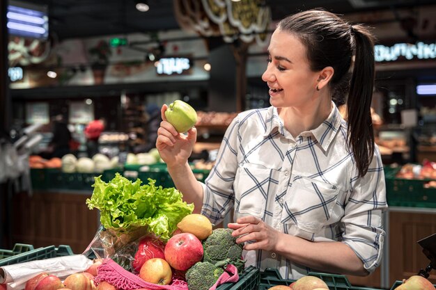 Una giovane donna sceglie frutta e verdura in un supermercato