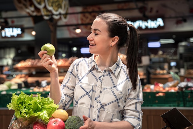 Una giovane donna sceglie frutta e verdura in un supermercato