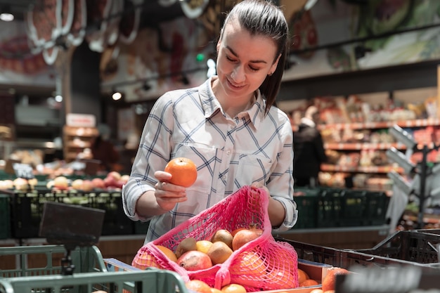 Una giovane donna sceglie la frutta in un supermercato