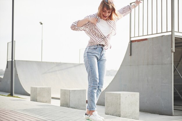 Una giovane donna sportiva che cavalca in un parco su uno skateboard.