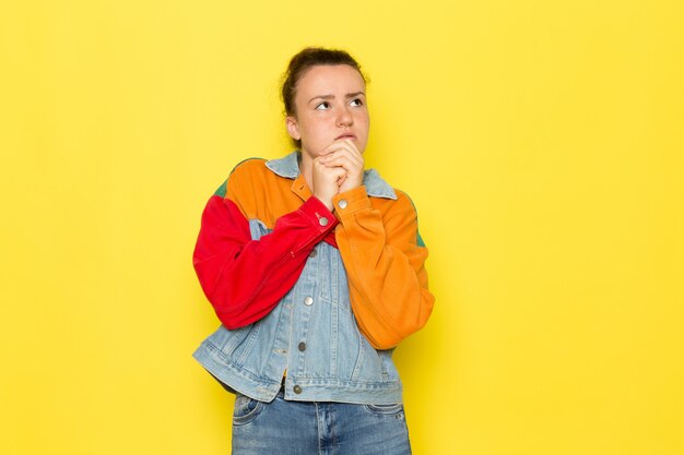 Una giovane donna vista frontale in giacca colorata camicia blu e jeans blu