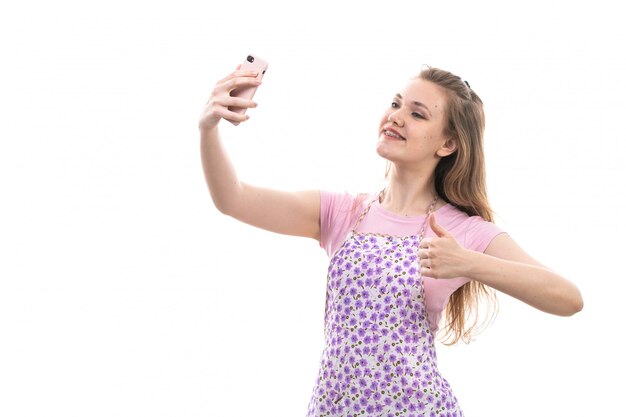 Una giovane e bella casalinga vista frontale in camicia rosa mantello colorato felice sorridente prendendo autoscatti