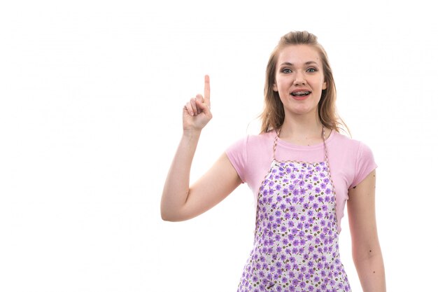 Una giovane e bella casalinga vista frontale in camicia rosa mantello colorato sorridendo felice con il dito alzato