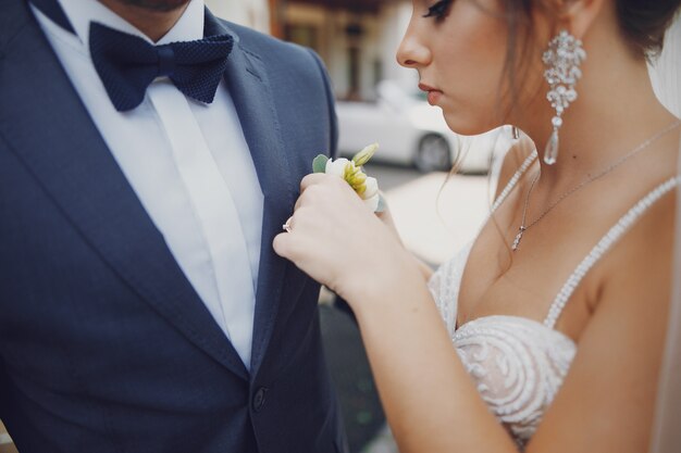 Una giovane e bella sposa è in piedi vicino a casa con suo marito