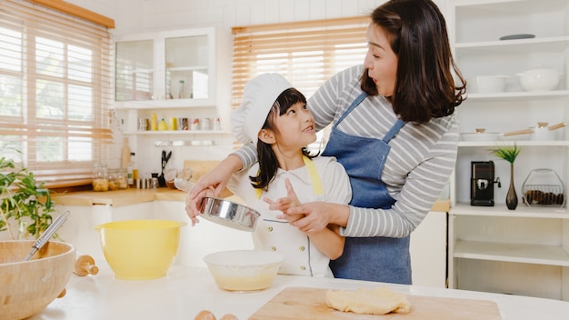 Una giovane famiglia giapponese asiatica sorridente felice con bambini in età prescolare si diverte a cucinare la pasticceria da forno