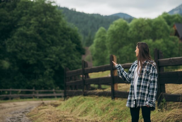 Una giovane femmina caucasica attraente che si siede su un recinto e che posa alla macchina fotografica