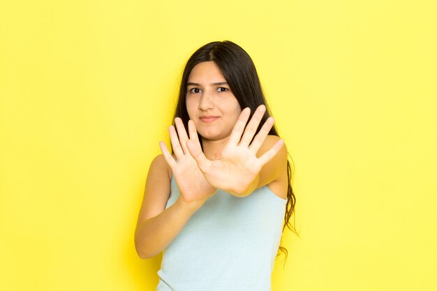 Una giovane femmina di vista frontale in camicia blu che posa sul modello di posa della ragazza del fondo giallo