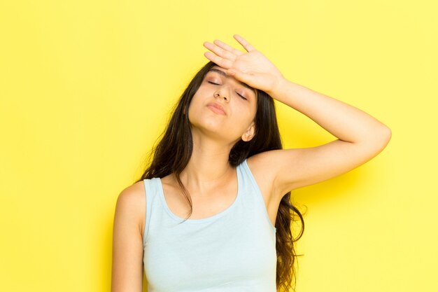 Una giovane femmina di vista frontale in camicia blu con una temperatura severa che tocca la sua fronte