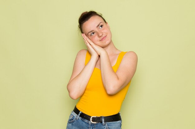 Una giovane femmina di vista frontale in camicia e blue jeans gialle con l'espressione della civetta