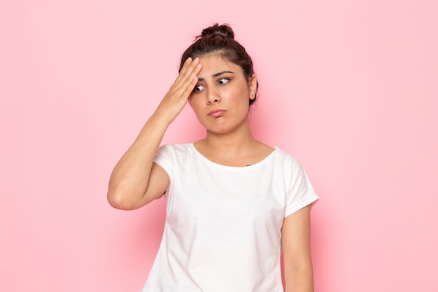 Una giovane femmina di vista frontale in maglietta bianca e blue jeans che posano con l'espressione confusa